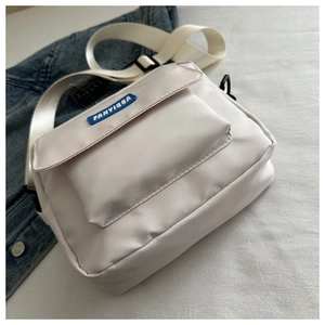 Dettaglio della borsa a tracolla in nylon bianco con patta frontale e tracolla larga
