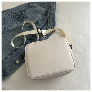 Dettaglio borsa a tracolla quadrata bianca con cinturino in nylon su denim blu