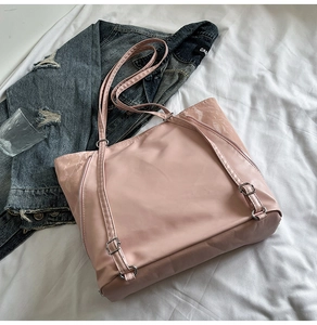 Detailed shot of pink nylon tote bag featuring silver metal buckles and textured side panels