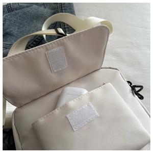 Close-up of canvas crossbody phone bag featuring velcro flap and front pocket detail