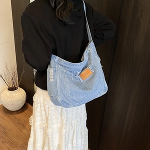 Sac bandoulière en jean bleu clair avec poches multiples et fini délavé sur modèle