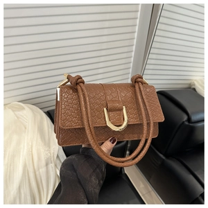Detail of a brown woven texture shoulder bag featuring a gold horseshoe metal buckle