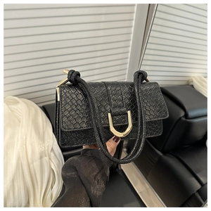 Detail of black snake-pattern leather handbag with golden U-shaped metal buckle