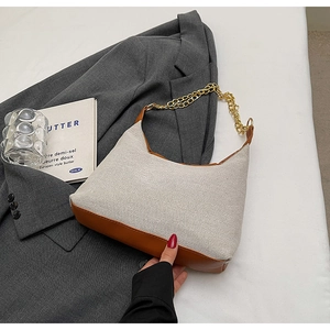 Dettaglio in tela beige e pelle marrone su una borsa shopping con tracolla a catena
