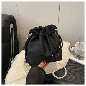 Close-up of black lace bucket bag with 3D floral details and pearl shoulder strap