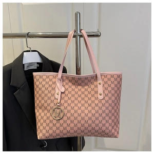 Détail du sac cabas rose avec motif à lettres M et pendentif doré métallique