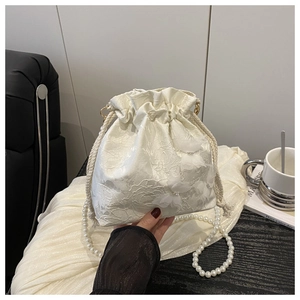 Close-up of white lace bucket bag with 3D butterfly motifs and elegant pearl strap