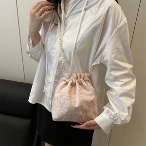 Pink lace bucket bag with 3D butterflies and pearl strap shown on model in studio
