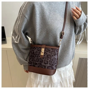 Détail du sac seau à motif léopard avec bordures en cuir marron et fermoir doré chic