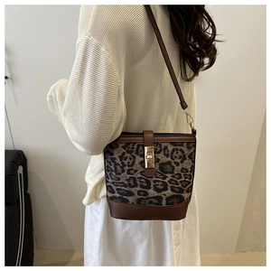 Modèle portant un sac seau léopard avec bordure en cuir marron et fermoir doré