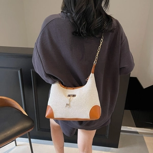 Borsa a spalla in tela con finiture in pelle marrone e ciondolo a cervo su modella