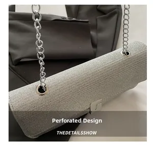 Detail of silver chain bag with eyelet design and metallic clasp on a black background