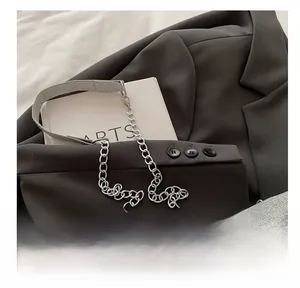 Detail of silver chain and woven fabric shoulder strap on a brown blazer with a book