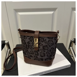 Détail du sac seau léopard avec bordure en cuir marron et boucle de verrouillage dorée