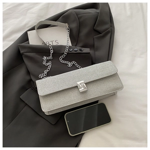 Detail of silver glitter crossbody bag with metallic turn-lock on grey blazer