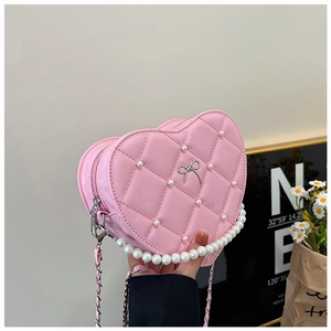 Macro view of pink heart-shaped bag featuring quilted texture and pearl embellishments