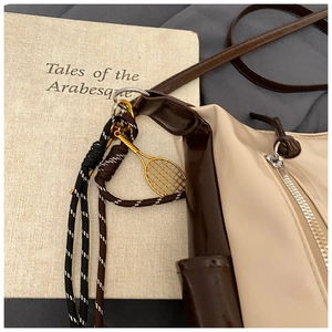 Détail d'un sac cabas beige et marron avec ornement en corde et charm de raquette de tennis