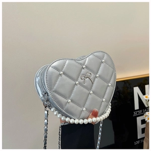 Detail showing silver heart-shaped quilted bag with white pearls and bow decoration