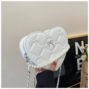 Detail of white heart-shaped bag with quilted diamond pattern and pearl embellishments