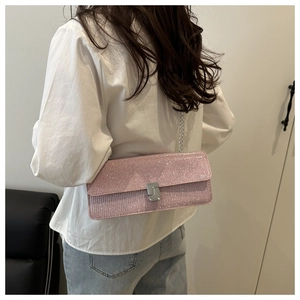 Detail of pink sequin crossbody bag with silver chain strap and metal lock on model