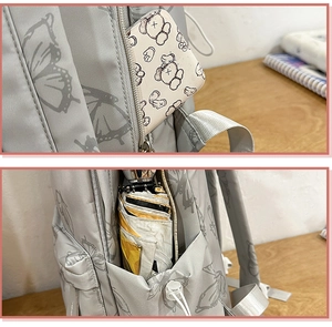 Detail of grey butterfly backpack showing functional side pockets and smooth metal zippers