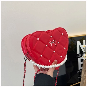 Detail of red heart-shaped quilted handbag with pearls, silver bow, and chain strap