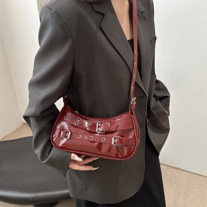 Sac à bandoulière chic en cuir verni bordeaux avec œillets argentés et boucles