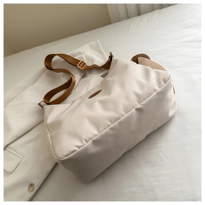 Detailansicht der cremefarbenen Nylontasche mit braunem Lederpatch und Trageriemen