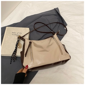 Détail du sac hobo rétro bicolore avec bandoulière et pendentif à pompon vintage