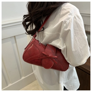Détail d'un sac à main rouge rétro avec nœud et texture cuir porté à l'épaule