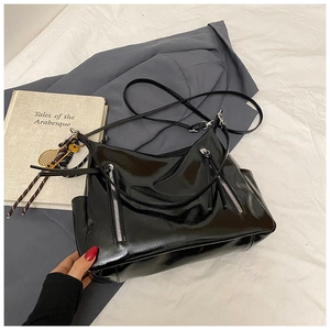 Détail d'un sac cabas noir brillant avec double fermeture éclair et poches latérales pratiques