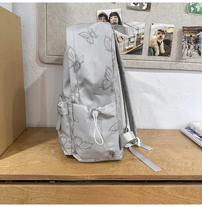 Close-up of grey butterfly print backpack featuring adjustable side drawstring pockets