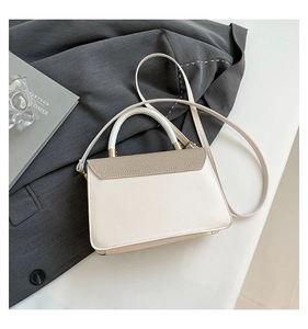 Detail of elegant cream handbag with champagne gold texture on grey blazer