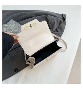 Detail view of cream shoulder bag interior with gold rotary lock and black lining