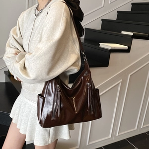 Deep brown oversized tote bag with glossy patent leather finish and stylish tassel accents