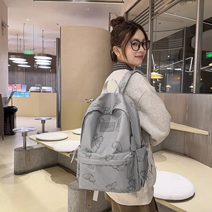 Detail of grey backpack with butterfly prints on person in a modern cafe setting