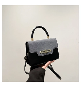 Detail of color-block handbag with gold twist lock and blue diagonal weave cover