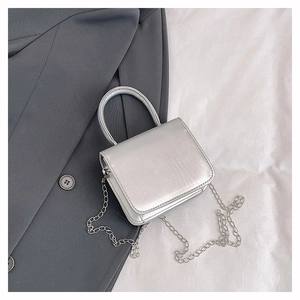 Detail of a mini silver handbag with bow design and detachable metal chain strap