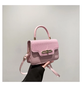 Detail of the pink crossbody bag featuring woven texture and gold metal buckle