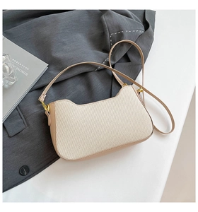 Detail of beige woven crossbody bag on a gray suit with high-quality golden hardware