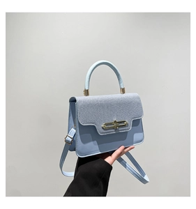 Detail of light blue leather handbag with golden rectangular hollow twist-lock and top handle