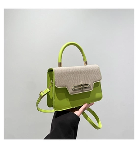 Detail of green leather handbag with beige woven flap and golden metal clasp closure