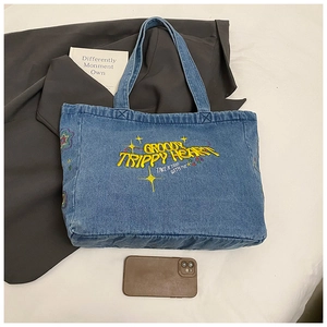 Close-up of retro denim tote with yellow Groovy Trippy Heart embroidery and star details