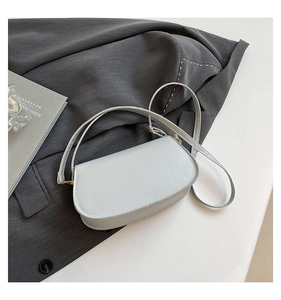 Détail du sac de selle bleu clair avec boucle en métal doré sur fond en tissu gris