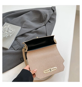 Detail of minimalist beige crossbody bag featuring textured flap and gold metal clasp