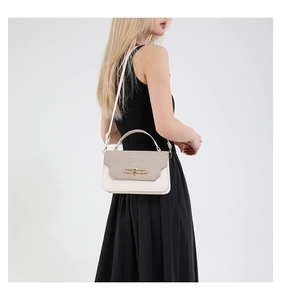 Detail of a chic cream and khaki crossbody bag with woven flap and gold metallic lock