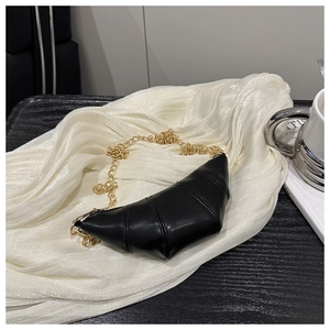 Detail of black crescent croissant bag featuring gold chain and luxury textured faux leather