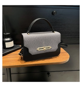 Detail of elegant two-tone handbag with gold buckle and adjustable shoulder strap