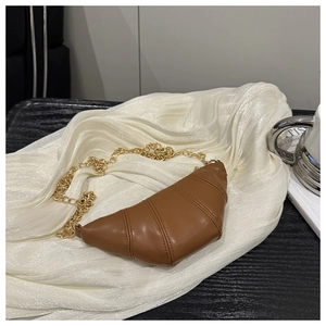 Detailed close-up of brown croissant bag with horizontal leather texture and gold chain