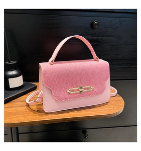Detailed view of pink woven flap and gold metal clasp on a stylish ladies' shoulder bag
